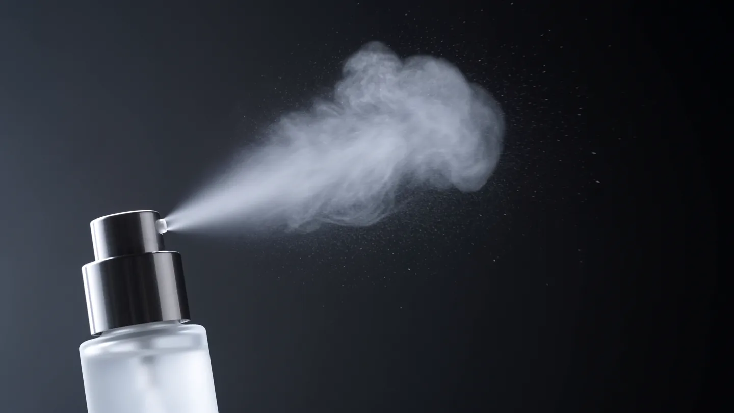 PLUME hero frame: mist bottle spraying cold white against the dark, wide